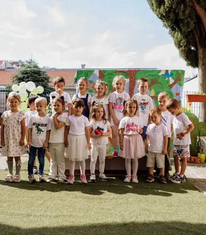 Group photo of about fifteen children in white in front of a painted backdrop