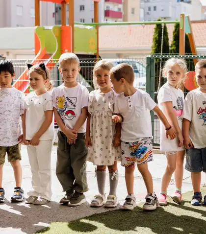 Seven children standing in a row by the playground on a sunny afternoon