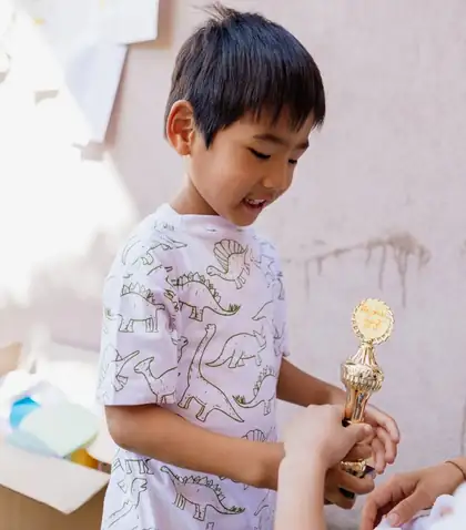 Smiling boy receiving a golden trophy with a handwritten medal