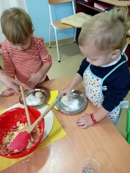 Two children making chocolate balls, a boy stirring the mixture in a red bowl