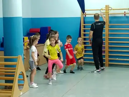 Sports class in the gym: children in colourful jerseys running in a line