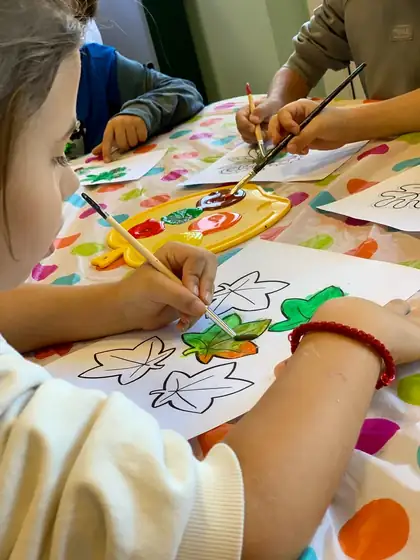 Children painting autumn leaves with watercolours at a polka-dot table
